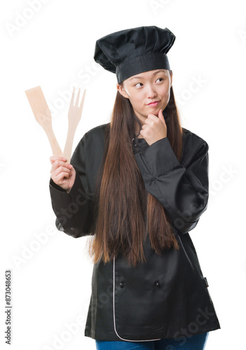 Young Chinese woman over isolated background wearing chef uniform serious face thinking about question, very confused idea