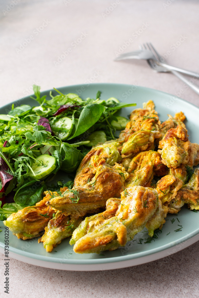 Fried zucchini flowers in batter and mix salad with cucumbers close up Fried zucchini flowers in batter and mix salad with cucumbers close up