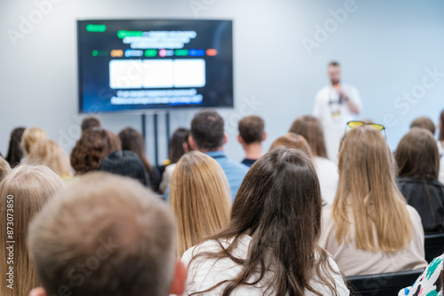 Wallpaper Mural Diverse audience attentively listening to a speaker during a business presentation in a modern conference room, with a large screen displaying information. Torontodigital.ca