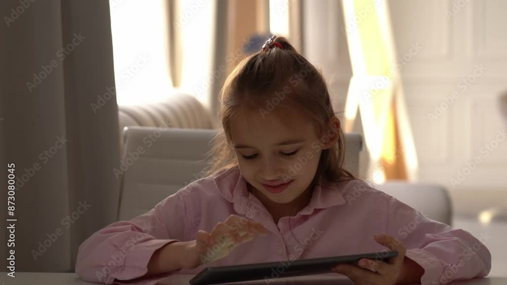 Happy Girl Using Tablet. Intensely focused on a gadget. Caucasian school girl Engaged With Tablet in Bright Living Room During Daytime Happy Girl Using Tablet. Intensely focused on a gadget. Caucasian school girl Engaged With Tablet in Bright Living Room During Daytime
