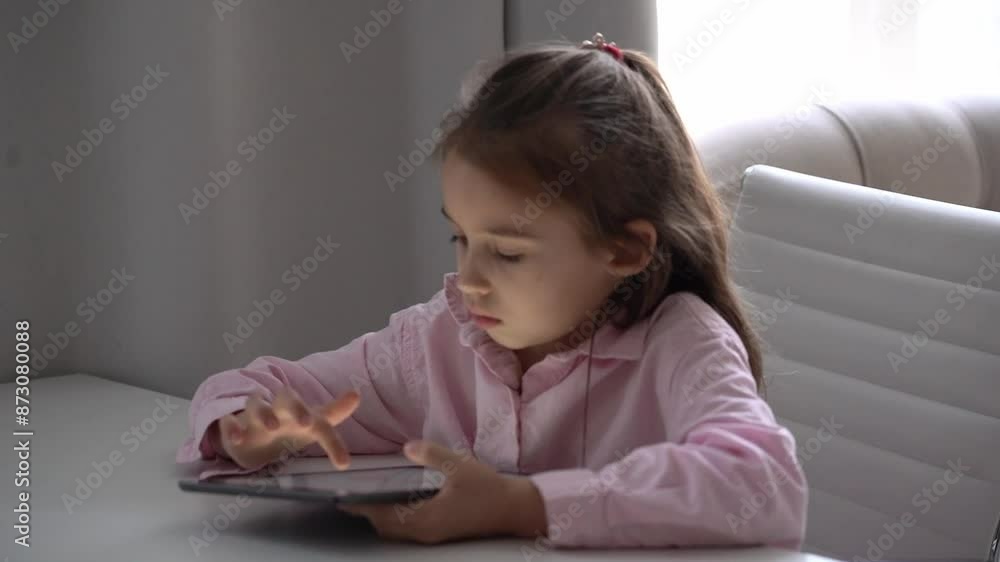 Girl Using Tablet. Intensely focused on a gadget. Caucasian school girl Engaged With Tablet in Bright Living Room Girl Using Tablet. Intensely focused on a gadget. Caucasian school girl Engaged With Tablet in Bright Living Room