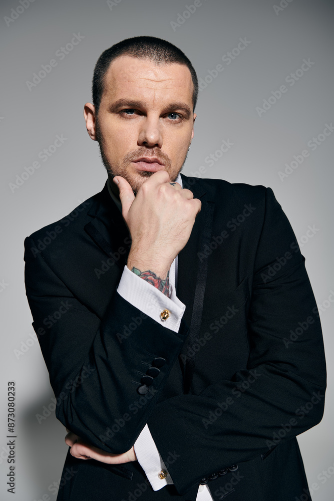 A man in a sharp black suit with a white shirt stares thoughtfully into the camera. A man in a sharp black suit with a white shirt stares thoughtfully into the camera.