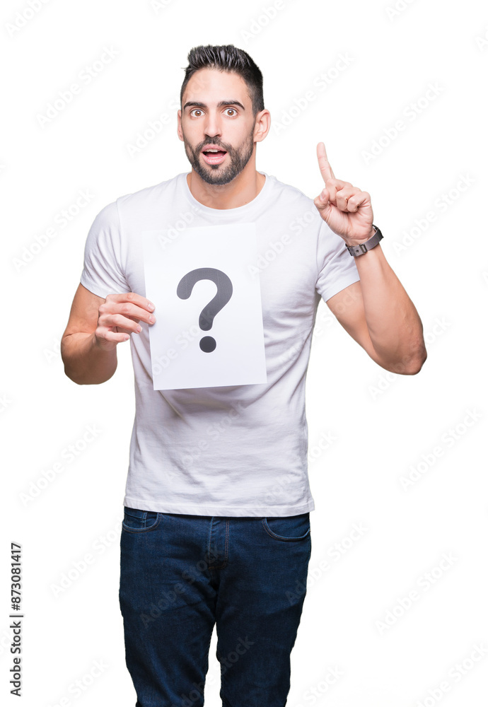 Handsome young man holding paper with question mark over isolated background surprised with an idea or question pointing finger with happy face, number one Handsome young man holding paper with question mark over isolated background surprised with an idea or question pointing finger with happy face, number one