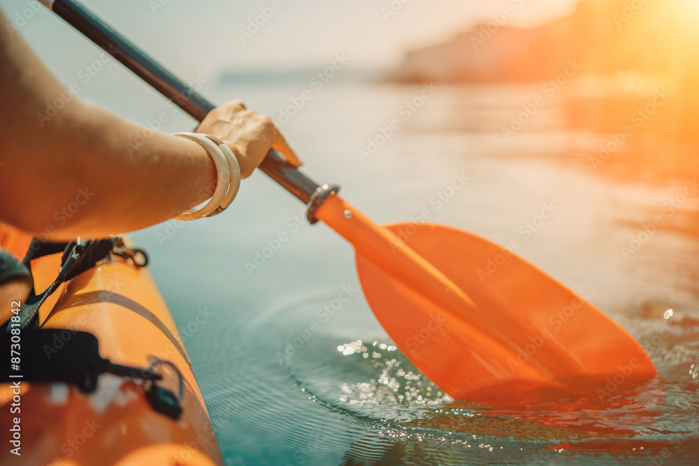 Fototapeta premium Kayak paddle sea vacation. Person paddles with orange paddle oar on kayak in sea. Leisure active lifestyle recreation activity rest tourism travel