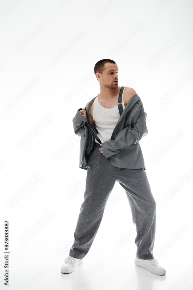 A man poses in a studio, adjusting his jacket with a confident air. A man poses in a studio, adjusting his jacket with a confident air.