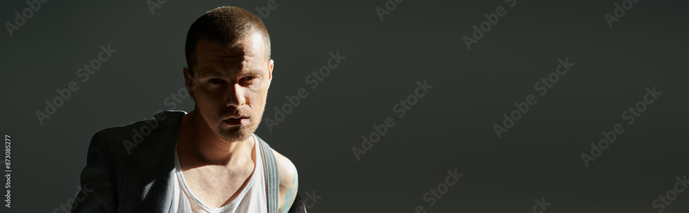 Fototapeta premium A stylish man poses against a dark background.