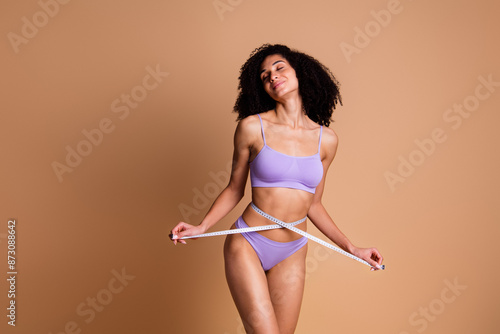 No filter portrait of stunning model girl measure waist closed eyes isolated on beige color background photo
