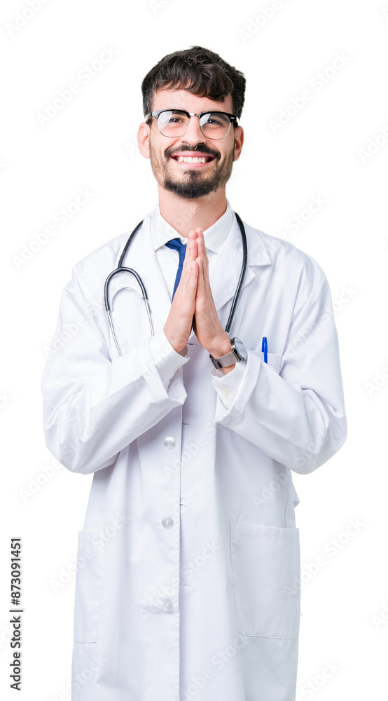 Young doctor man wearing hospital coat over isolated background praying with hands together asking for forgiveness smiling confident. Young doctor man wearing hospital coat over isolated background praying with hands together asking for forgiveness smiling confident.