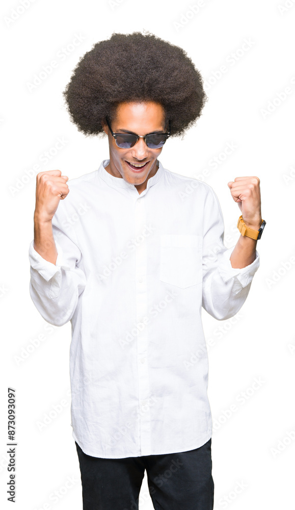 Young african american man with afro hair wearing sunglasses very happy and excited doing winner gesture with arms raised, smiling and screaming for success. Celebration concept. Young african american man with afro hair wearing sunglasses very happy and excited doing winner gesture with arms raised, smiling and screaming for success. Celebration concept.