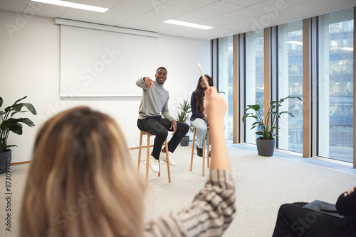 Businessman pointing at colleague to ask question during meeting in office photo