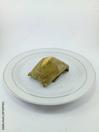 Beppa Oto: A Traditional Bugis Dessert from Sulawesi, Indonesia. Made of Banana and Wrapped in Banana Leaf, Presented on a White Background, Highlighting Rich Cultural Heritage and Culinary Tradition photo