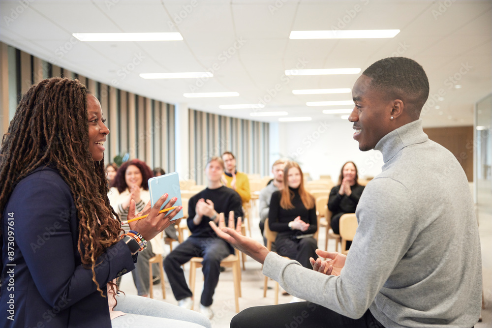 Smiling businessman and businesswoman giving presentation to colleagues in office Smiling businessman and businesswoman giving presentation to colleagues in office