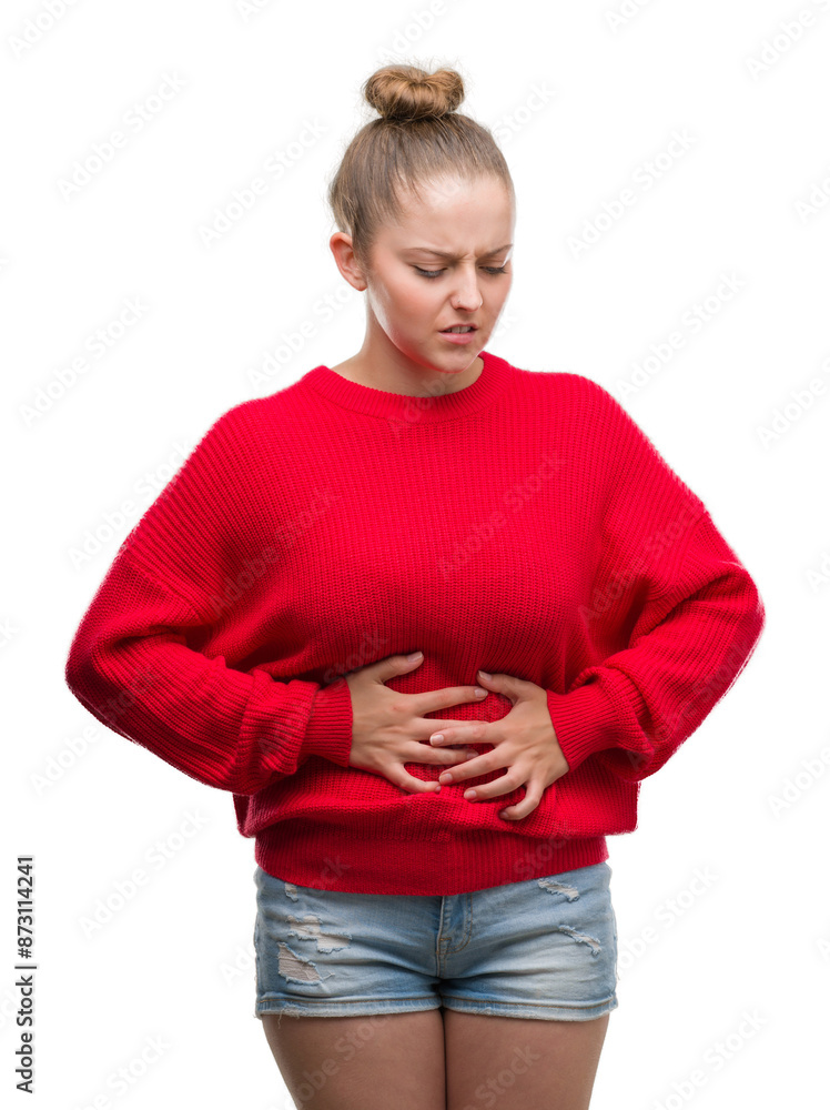 Young blonde woman wearing bun and red sweater with hand on stomach because indigestion, painful illness feeling unwell. Ache concept. Young blonde woman wearing bun and red sweater with hand on stomach because indigestion, painful illness feeling unwell. Ache concept.