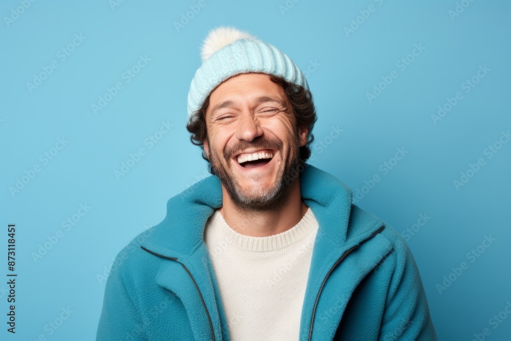 Portrait of a joyful man in his 40s dressed in a warm ski hat isolated in pastel blue background Portrait of a joyful man in his 40s dressed in a warm ski hat isolated in pastel blue background