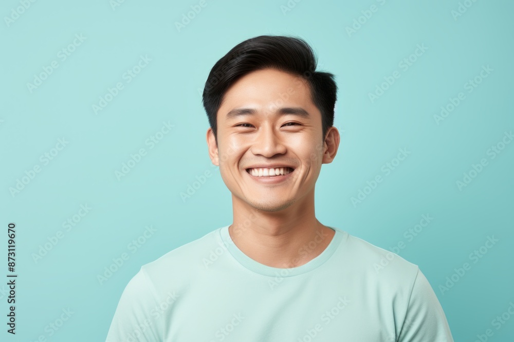 Portrait of a smiling asian man in his 20s wearing a breathable golf polo in front of pastel blue background Portrait of a smiling asian man in his 20s wearing a breathable golf polo in front of pastel blue background