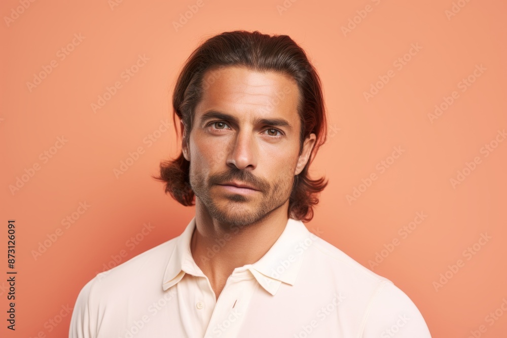 Fototapeta premium Portrait of a tender man in his 30s donning a trendy cropped top isolated in pastel orange background