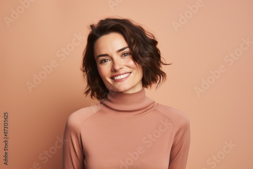 Portrait of a glad woman in her 30s wearing a classic turtleneck sweater in front of pastel brown background © Markus Schröder