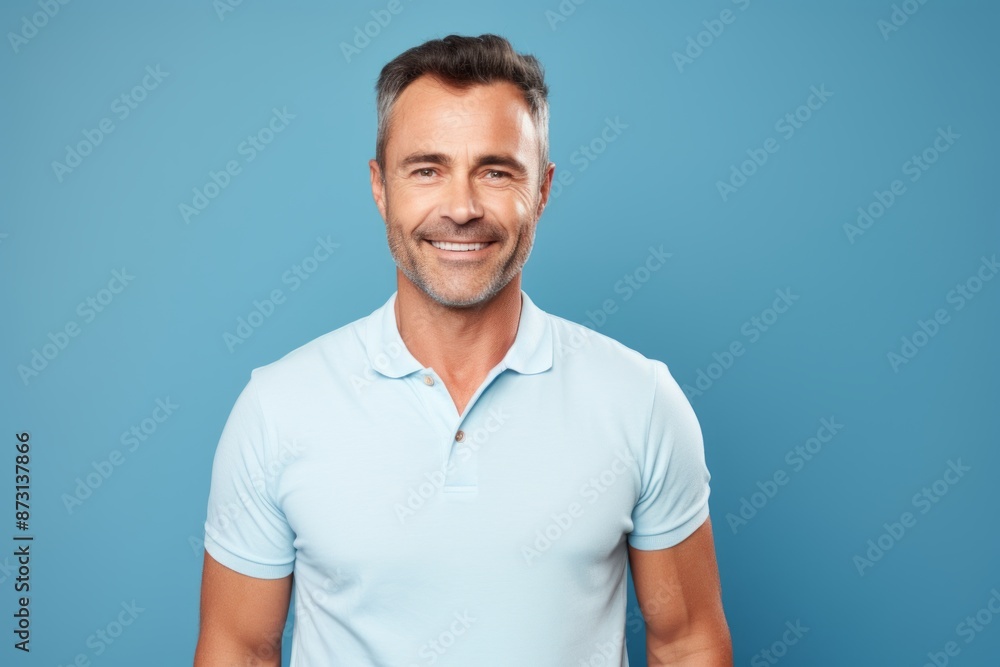 Portrait of a satisfied man in his 40s wearing a sporty polo shirt in soft blue background Portrait of a satisfied man in his 40s wearing a sporty polo shirt in soft blue background