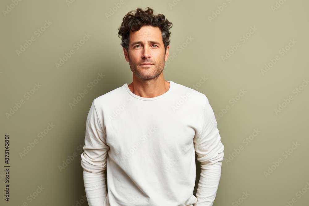 Portrait of a grinning man in his 30s sporting a long-sleeved thermal undershirt in front of soft green background Portrait of a grinning man in his 30s sporting a long-sleeved thermal undershirt in front of soft green background