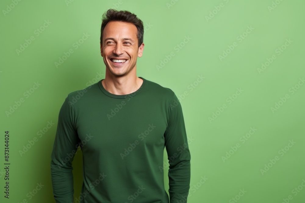 Portrait of a grinning man in his 30s sporting a long-sleeved thermal undershirt in soft green background Portrait of a grinning man in his 30s sporting a long-sleeved thermal undershirt in soft green background