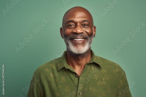 Portrait of a satisfied afro-american man in his 50s wearing a chic cardigan isolated on soft green background © Markus Schröder