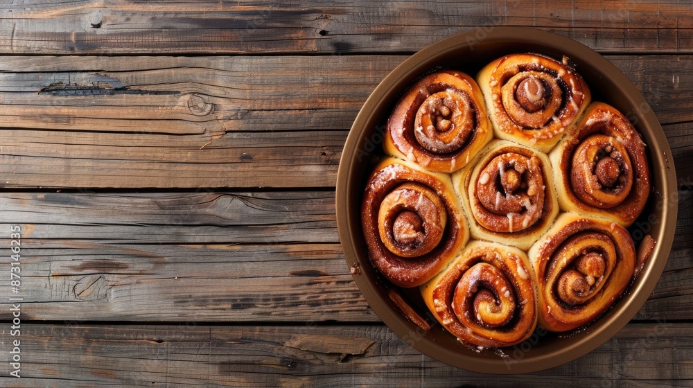 Freshly baked cinnamon rolls with frosting in a pan on rustic wood with space for text Freshly baked cinnamon rolls with frosting in a pan on rustic wood with space for text