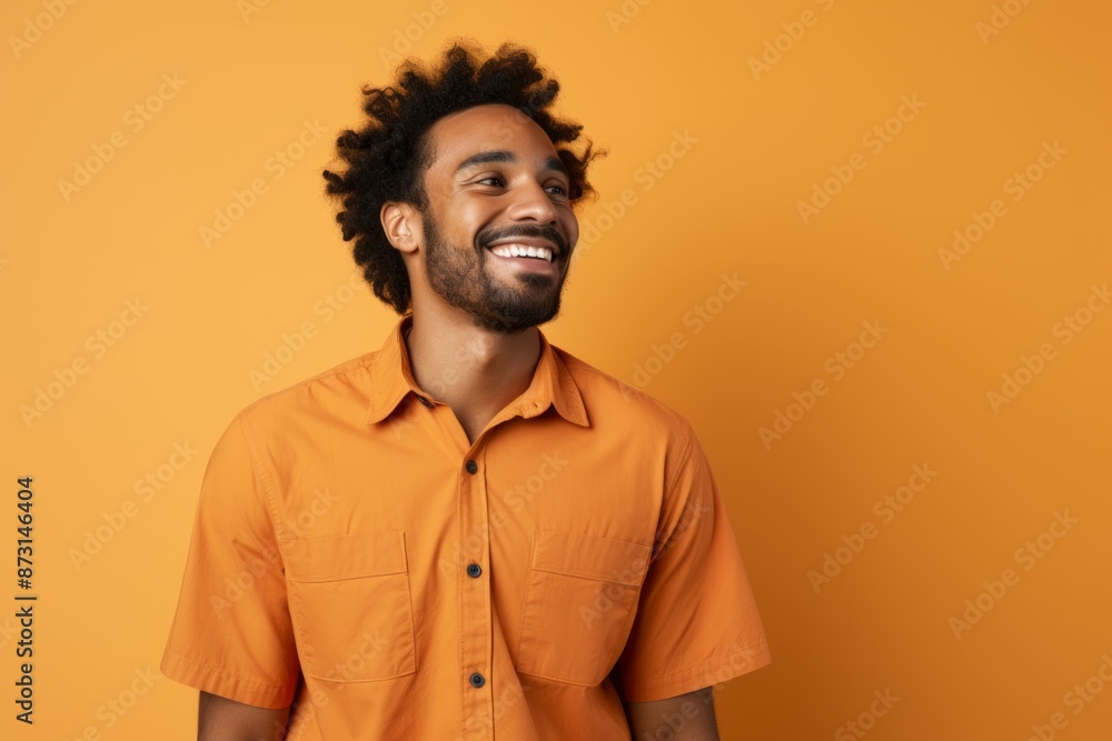 Portrait of a jovial afro-american man in his 30s sporting a breathable hiking shirt isolated on soft orange background Portrait of a jovial afro-american man in his 30s sporting a breathable hiking shirt isolated on soft orange background