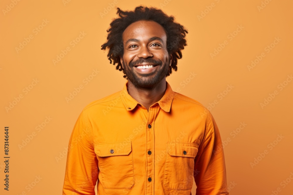 Fototapeta premium Portrait of a jovial afro-american man in his 30s sporting a breathable hiking shirt isolated in soft orange background