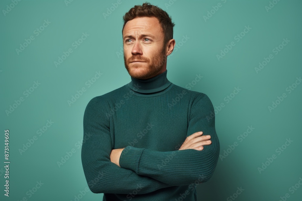 Portrait of a satisfied man in his 30s wearing a classic turtleneck sweater over soft teal background Portrait of a satisfied man in his 30s wearing a classic turtleneck sweater over soft teal background