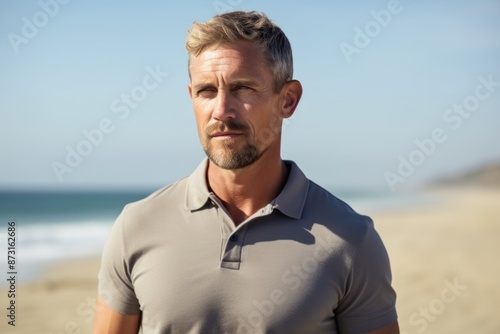 Portrait of a tender man in his 40s donning a classy polo shirt on sandy beach background