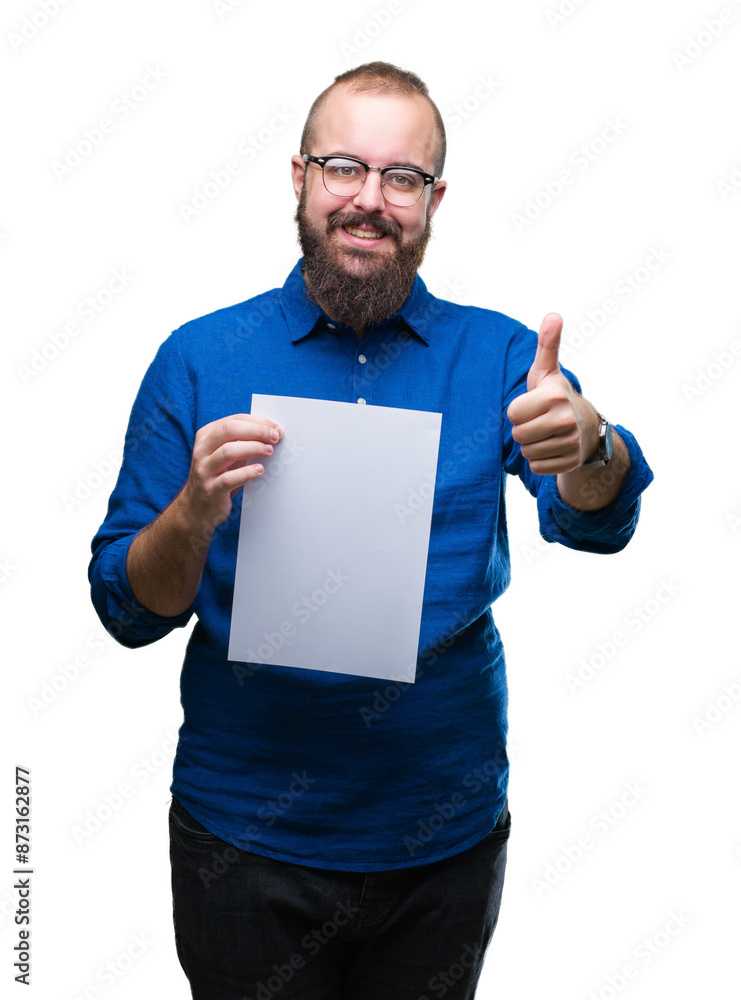 Young hipster man wearing glasses and holding blank paper over isolated background happy with big smile doing ok sign, thumb up with fingers, excellent sign Young hipster man wearing glasses and holding blank paper over isolated background happy with big smile doing ok sign, thumb up with fingers, excellent sign