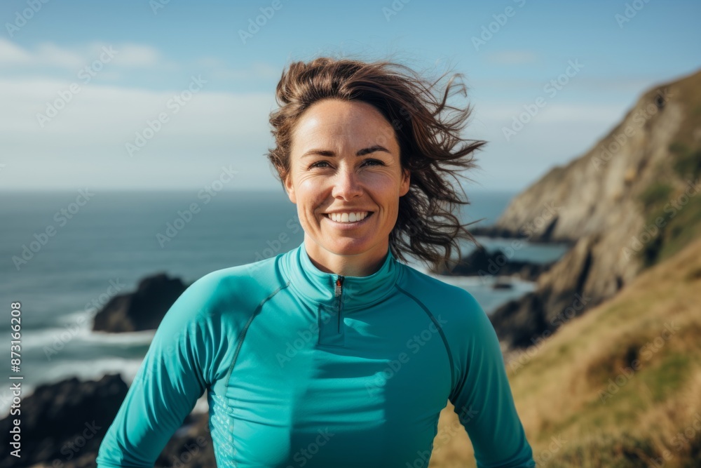 Portrait of a grinning woman in her 30s sporting a technical climbing shirt isolated in serene seaside background Portrait of a grinning woman in her 30s sporting a technical climbing shirt isolated in serene seaside background