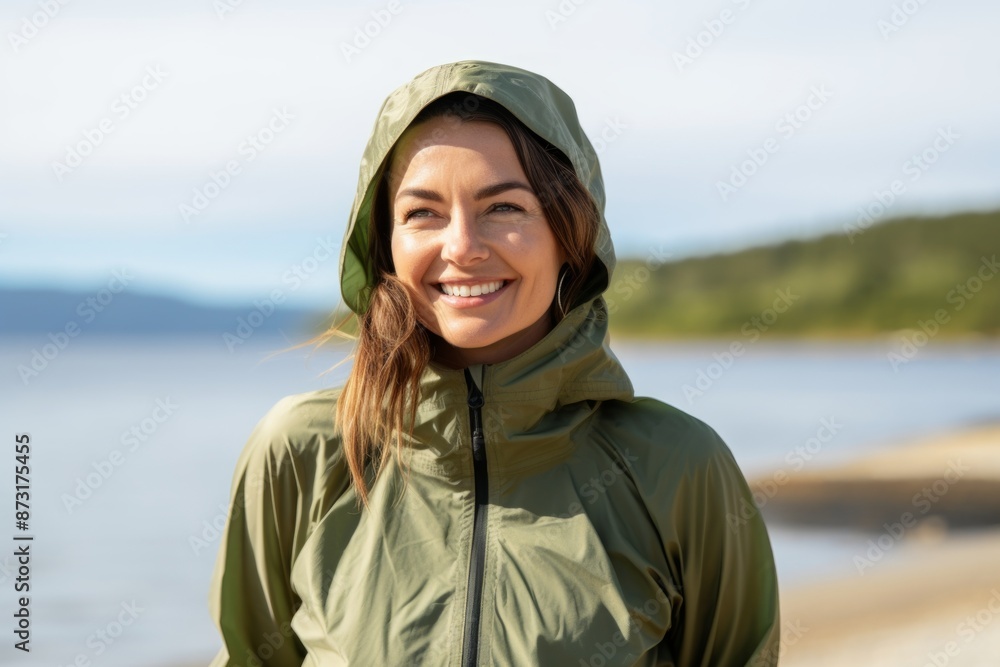 Portrait of a jovial woman in her 30s wearing a lightweight packable anorak over beautiful lagoon background Portrait of a jovial woman in her 30s wearing a lightweight packable anorak over beautiful lagoon background