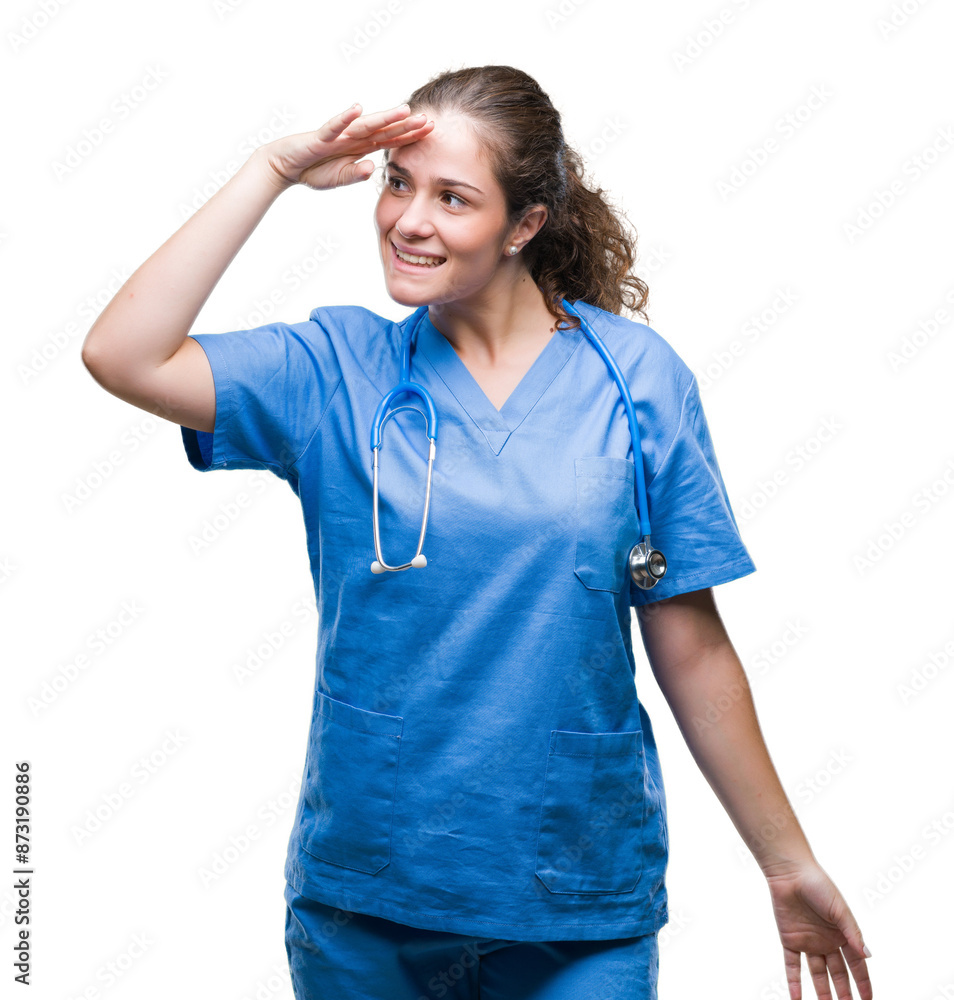 Young brunette doctor girl wearing nurse or surgeon uniform over isolated background very happy and smiling looking far away with hand over head. Searching concept. Young brunette doctor girl wearing nurse or surgeon uniform over isolated background very happy and smiling looking far away with hand over head. Searching concept.