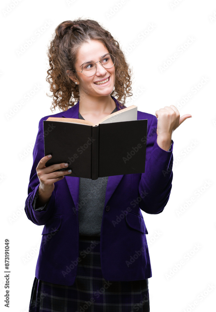 Young brunette student girl wearing school uniform reading a book over isolated background pointing and showing with thumb up to the side with happy face smiling Young brunette student girl wearing school uniform reading a book over isolated background pointing and showing with thumb up to the side with happy face smiling
