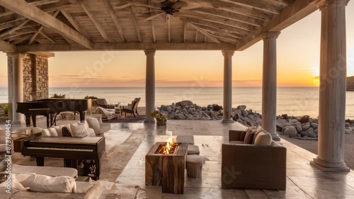  an outdoor living room with an open roof and furniture in front by the ocean at sunset near sea with setting sun behind a piano and fireplace table surrounded by columns