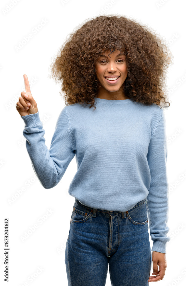 African american woman wearing a sweater showing and pointing up with finger number one while smiling confident and happy. African american woman wearing a sweater showing and pointing up with finger number one while smiling confident and happy.
