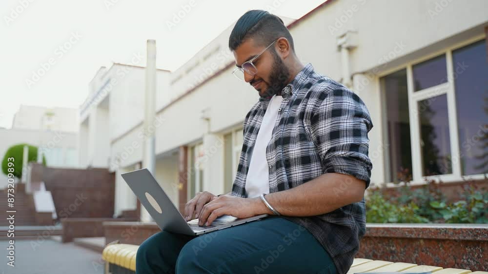 Indian student preparing for exams outdoor with laptop in university campus Indian student preparing for exams outdoor with laptop in university campus