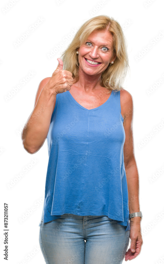 Middle age blonde woman over isolated background doing happy thumbs up gesture with hand. Approving expression looking at the camera with showing success. Middle age blonde woman over isolated background doing happy thumbs up gesture with hand. Approving expression looking at the camera with showing success.