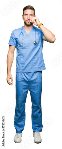 Handsome doctor man wearing medical uniform over isolated background mouth and lips shut as zip with fingers. Secret and silent, taboo talking