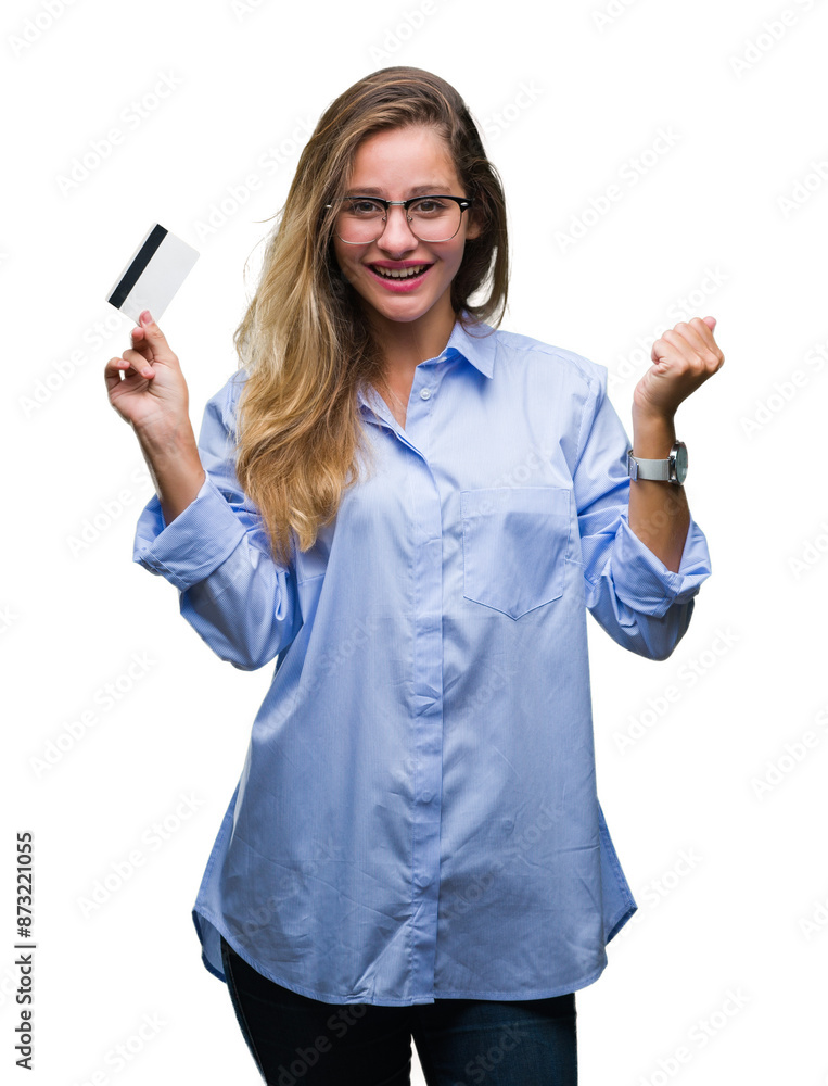 Young beautiful blonde woman holding credit card over isolated background screaming proud and celebrating victory and success very excited, cheering emotion Young beautiful blonde woman holding credit card over isolated background screaming proud and celebrating victory and success very excited, cheering emotion