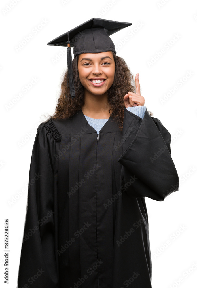 Young hispanic woman wearing graduation uniform surprised with an idea or question pointing finger with happy face, number one Young hispanic woman wearing graduation uniform surprised with an idea or question pointing finger with happy face, number one