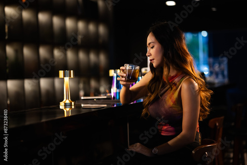 A woman drinks alcohol and gets drunk at a bar at night.