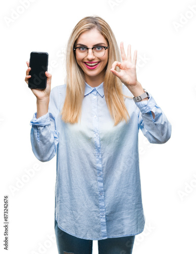 Young beautiful blonde business woman showing screen of smartphone over isolated background doing ok sign with fingers, excellent symbol