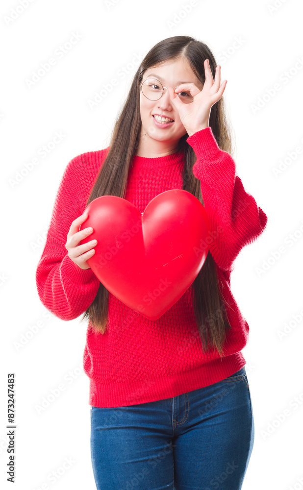 Young Chinese woman wearing graduate uniform red heart with happy face smiling doing ok sign with hand on eye looking through fingers Young Chinese woman wearing graduate uniform red heart with happy face smiling doing ok sign with hand on eye looking through fingers