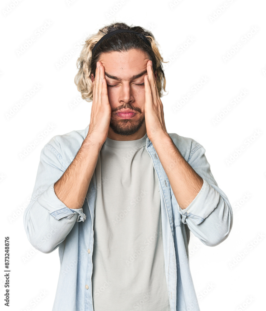 Naklejka premium Young Caucasian man in studio setting touching temples and having headache.