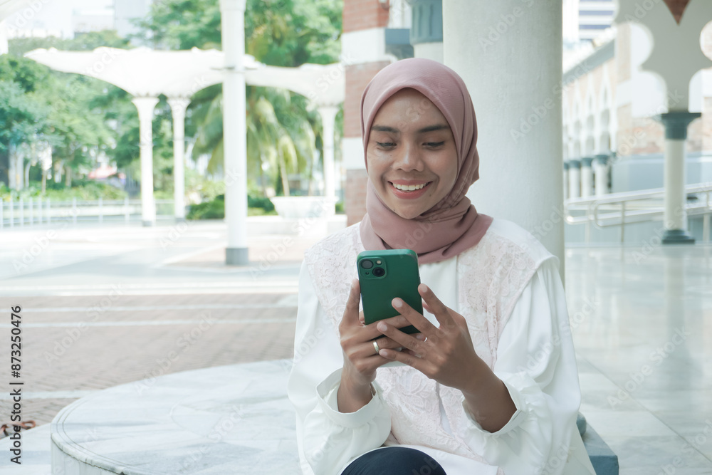 Fototapeta premium A smilling woman sitting using cell phone