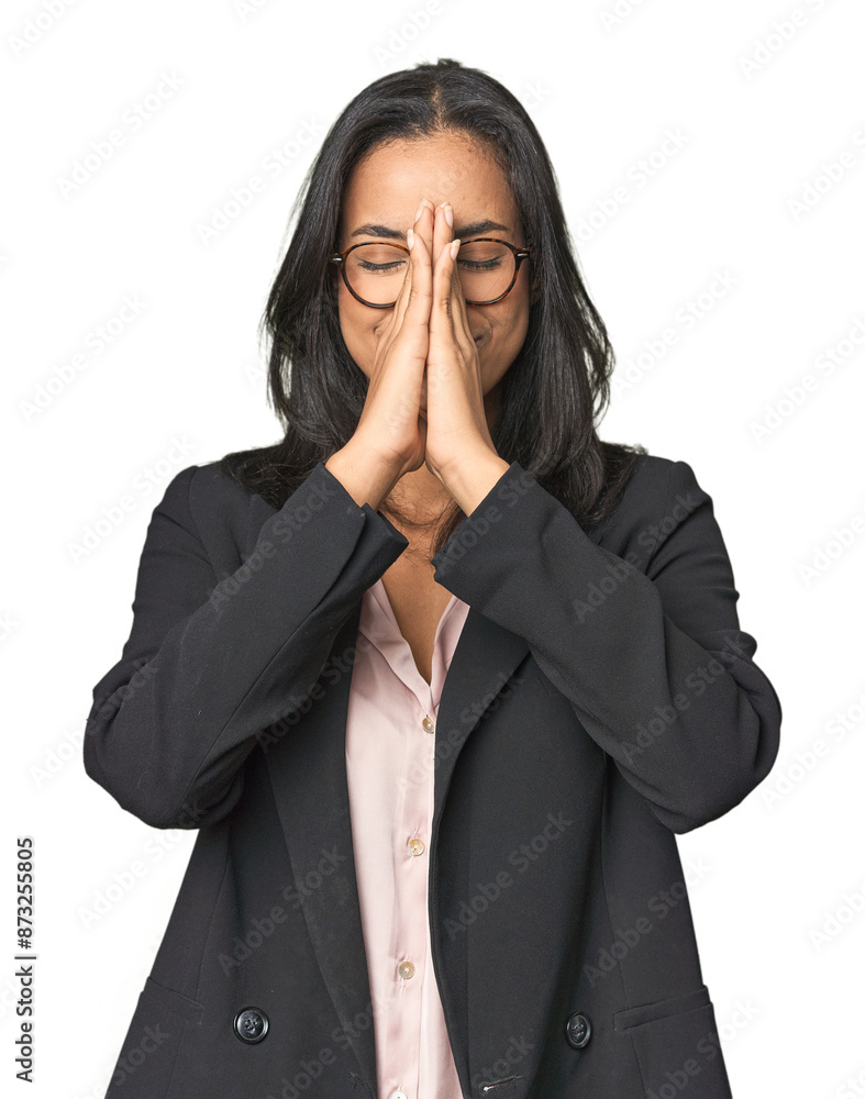 Young Latina professional in studio holding hands in pray near mouth, feels confident. Young Latina professional in studio holding hands in pray near mouth, feels confident.