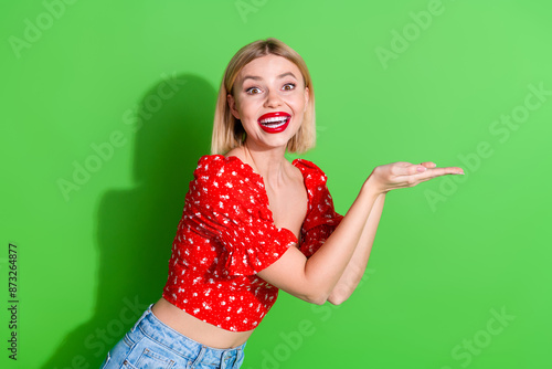 Photo of cheerful glad lovely cute woman wear red trendy clothes hold brand empty space isolated on green color background