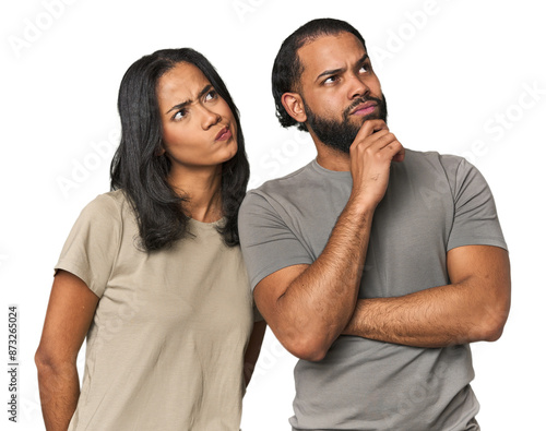 Canvas Print Young Latino couple in studio thinking and looking up, being reflective, contemplating, having a fantasy